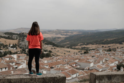 Rear view of woman standing on mountain against sky