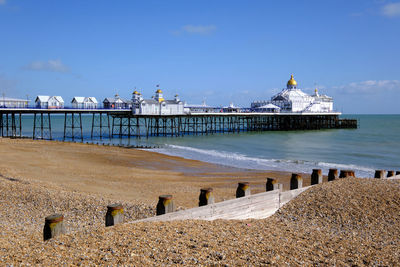 Eastbourne pier and beach on a sunny day with a groyne in the foreground