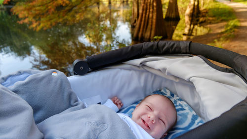 Close-up of baby boy lying in stroller by lake