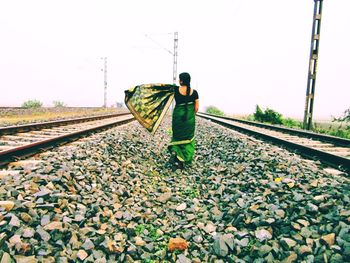 Man standing on railroad track against clear sky