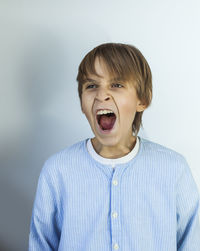 Boy yawning against white background
