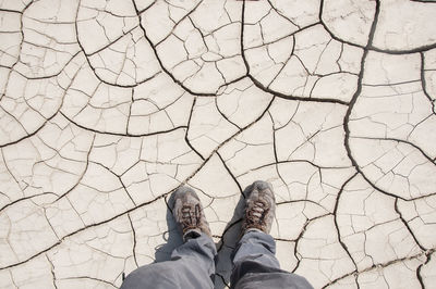 Low section of man standing on dried cracked soil during draught