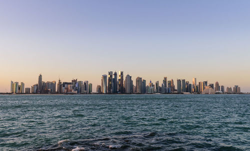 Sea and cityscape against clear sky