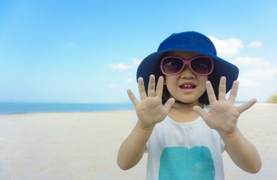 Portrait of young girl wearing sunglasses and hat against clear blue sky