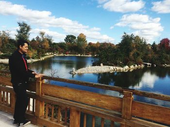 Man standing by railing against sky