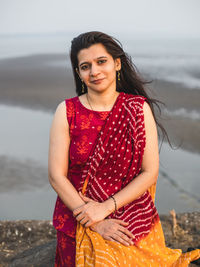 Portrait of a smiling young woman standing at sea