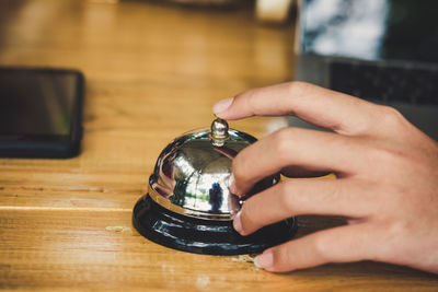 Cropped hand of man ringing service bell on desk