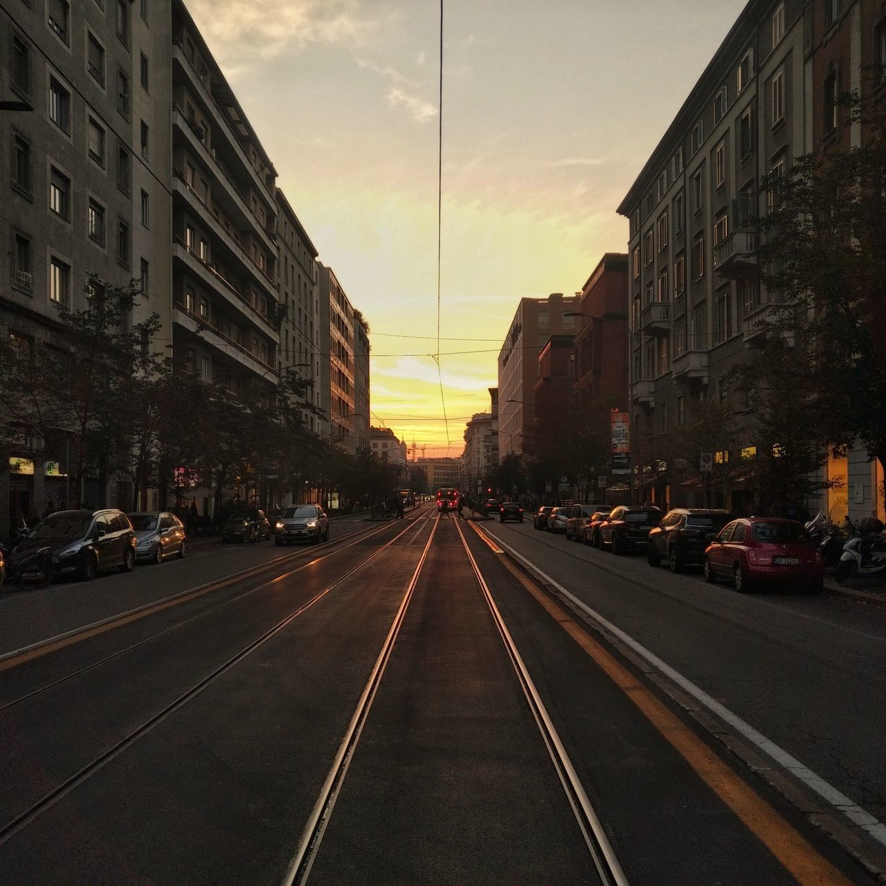 ROAD AMIDST BUILDINGS IN CITY AT SUNSET