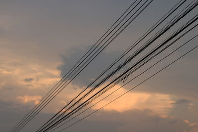 Low angle view of power lines against sky during sunset