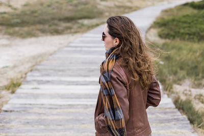 Side view of woman standing on boardwalk