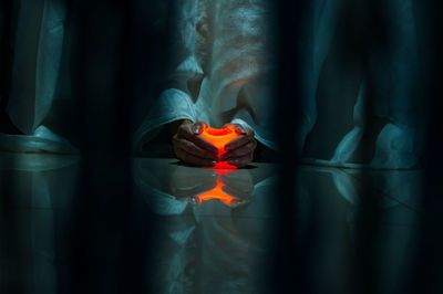 Artistic close - up of a woman's hands embracing a candle 