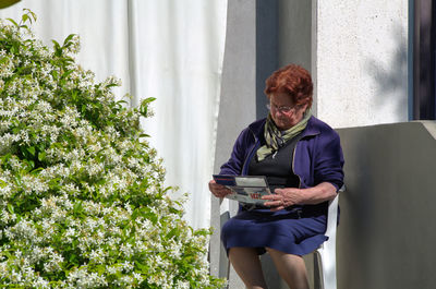 Full length of woman sitting on mobile phone