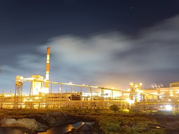 Illuminated bridge over river against sky at night