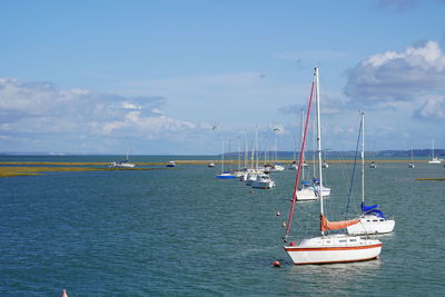 Sailboats moored in sea against sky