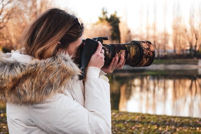 Side view of woman photographing with camera