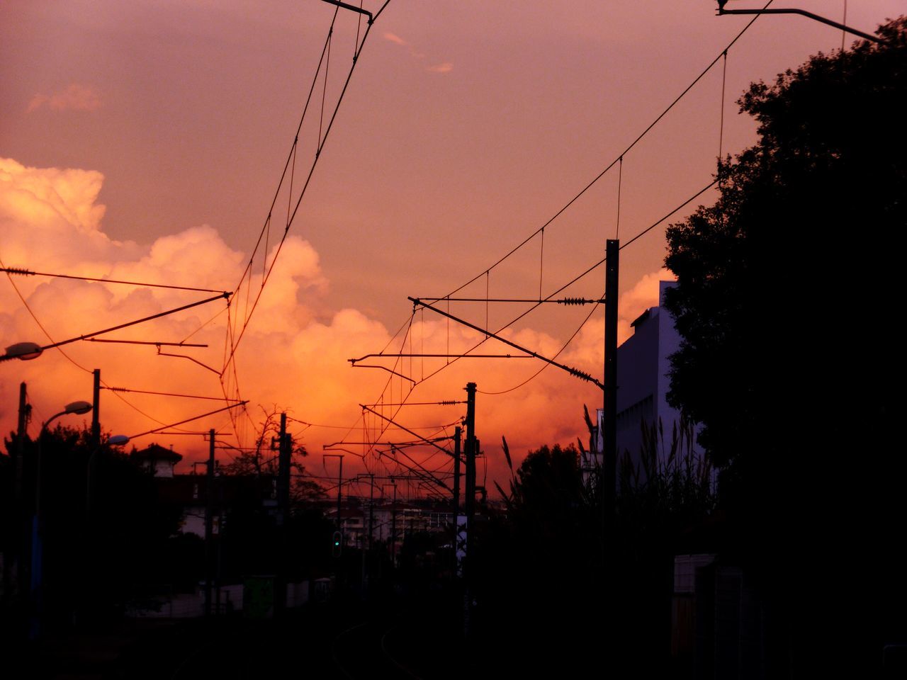 sunset, power line, electricity pylon, silhouette, building exterior, electricity, orange color, power supply, sky, built structure, cable, architecture, fuel and power generation, technology, connection, tree, house, power cable, outdoors, nature