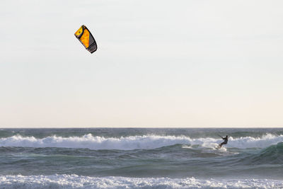 Mid distance view of silhouette person kitesurfing on sea