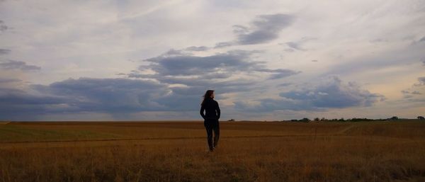 Rear view of man standing on field against sky