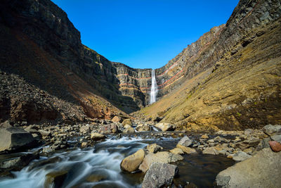 Scenic view of stream amidst rocks against sky