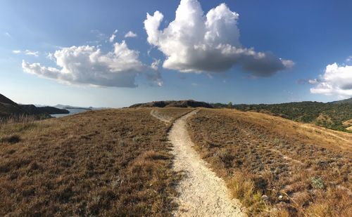 Scenic view of dirt road against sky