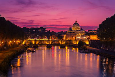 Illuminated bridge over river against sky at sunset