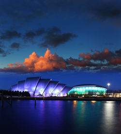 Illuminated bridge over river against sky at night