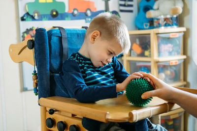 Full length of boy sitting on table at home