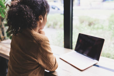 Young african woman working on her laptop in cafeteria. over shoulder shot