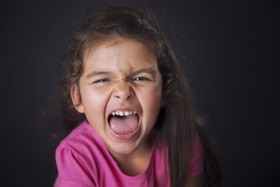 Close-up portrait of girl against black background