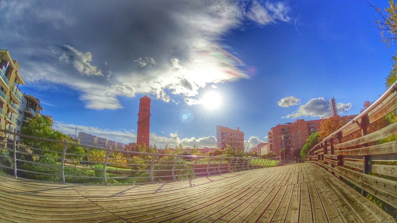 sky, the way forward, cloud - sky, architecture, built structure, diminishing perspective, blue, vanishing point, tree, building exterior, transportation, cloud, sunlight, nature, outdoors, sunbeam, no people, day, cloudy, railroad track