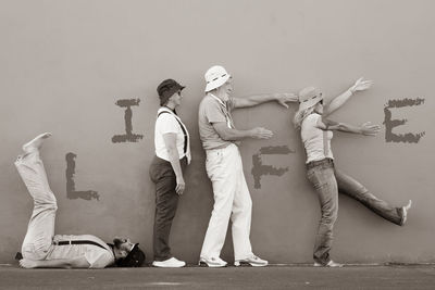 Friends making life text while standing by wall