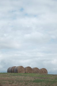 Hay bales on field against sky