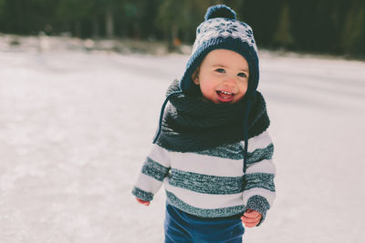 Smiling boy standing on snow covered field