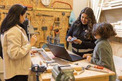 Female technician discussing over electronic goods with boy at recycling center