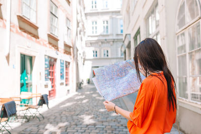 Woman standing on street amidst buildings in city