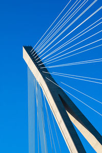 Low angle view of suspension bridge against clear blue sky