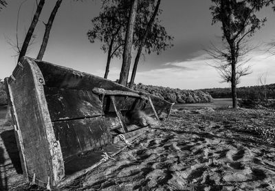 Abandoned boat on field against sky