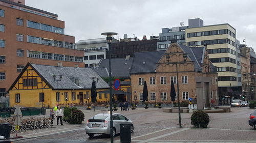 Road by buildings in city against sky