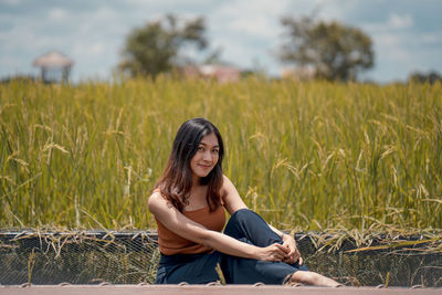 Portrait of young woman sitting on field