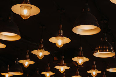 Low angle view of illuminated pendant lights hanging from ceiling