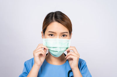 Portrait of a young woman wearing mask against white background