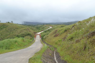 Road leading towards mountain against sky