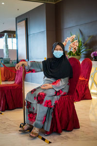 Senior woman wearing mask sitting on chair