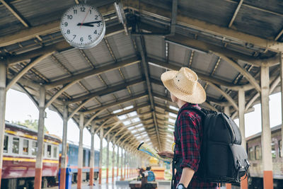 Rear view of woman standing at railroad station