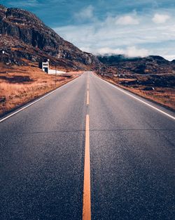 Empty road against cloudy sky