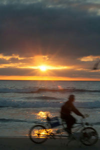 Silhouette man on beach against sky during sunset