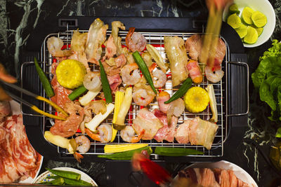 Cropped hands of people preparing food on barbecue grill