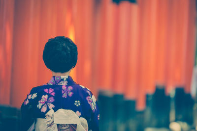 Rear view of woman standing against torii gates at fushimi inari shrine