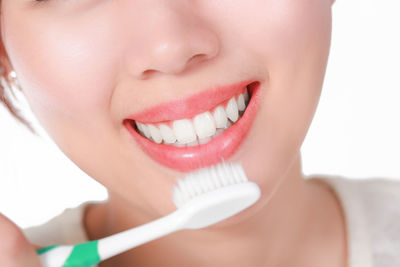 Close-up of woman brushing teeth over white background