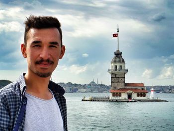 Portrait of young man standing by sea with maidens tower in background